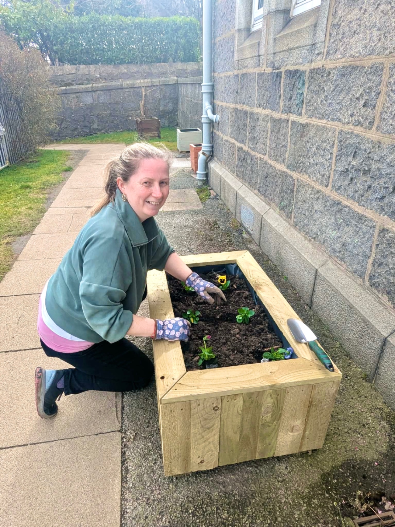 Pam from Balance and Bloom planting a community raised bed in Aberdeen